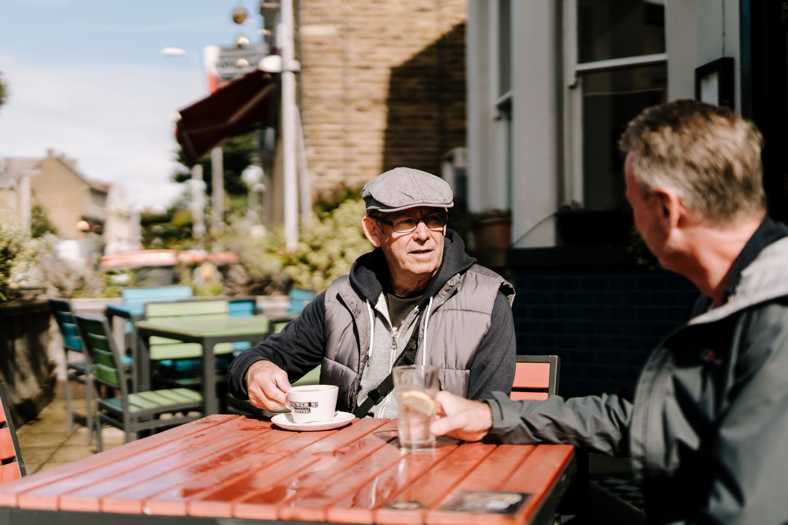 Two friends chatting over coffee on a sunny café terrace